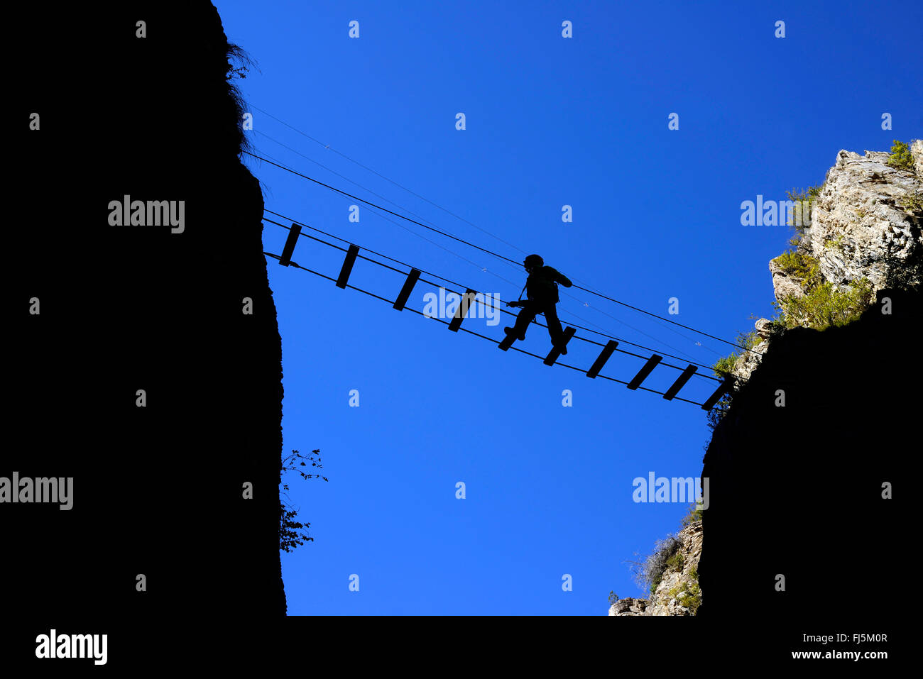 climber crossing the canyon on a suspension bridge, Durance Canyon, France, Hautes Alpes, Chateau Queyras Stock Photo