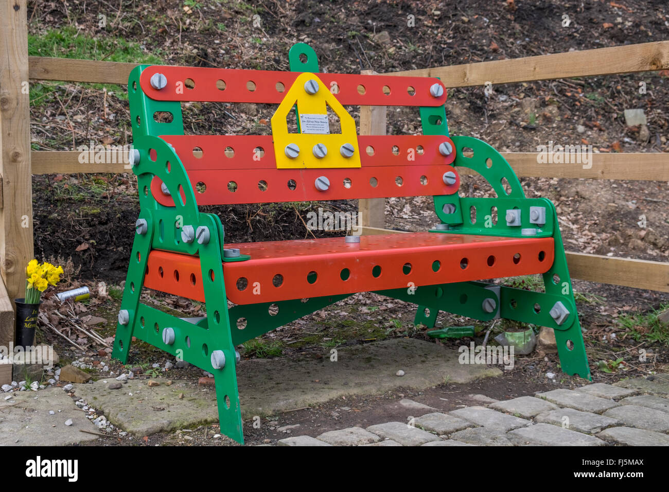 A Red and Green  Meccano style bench with flowers in a memorial vase Stock Photo