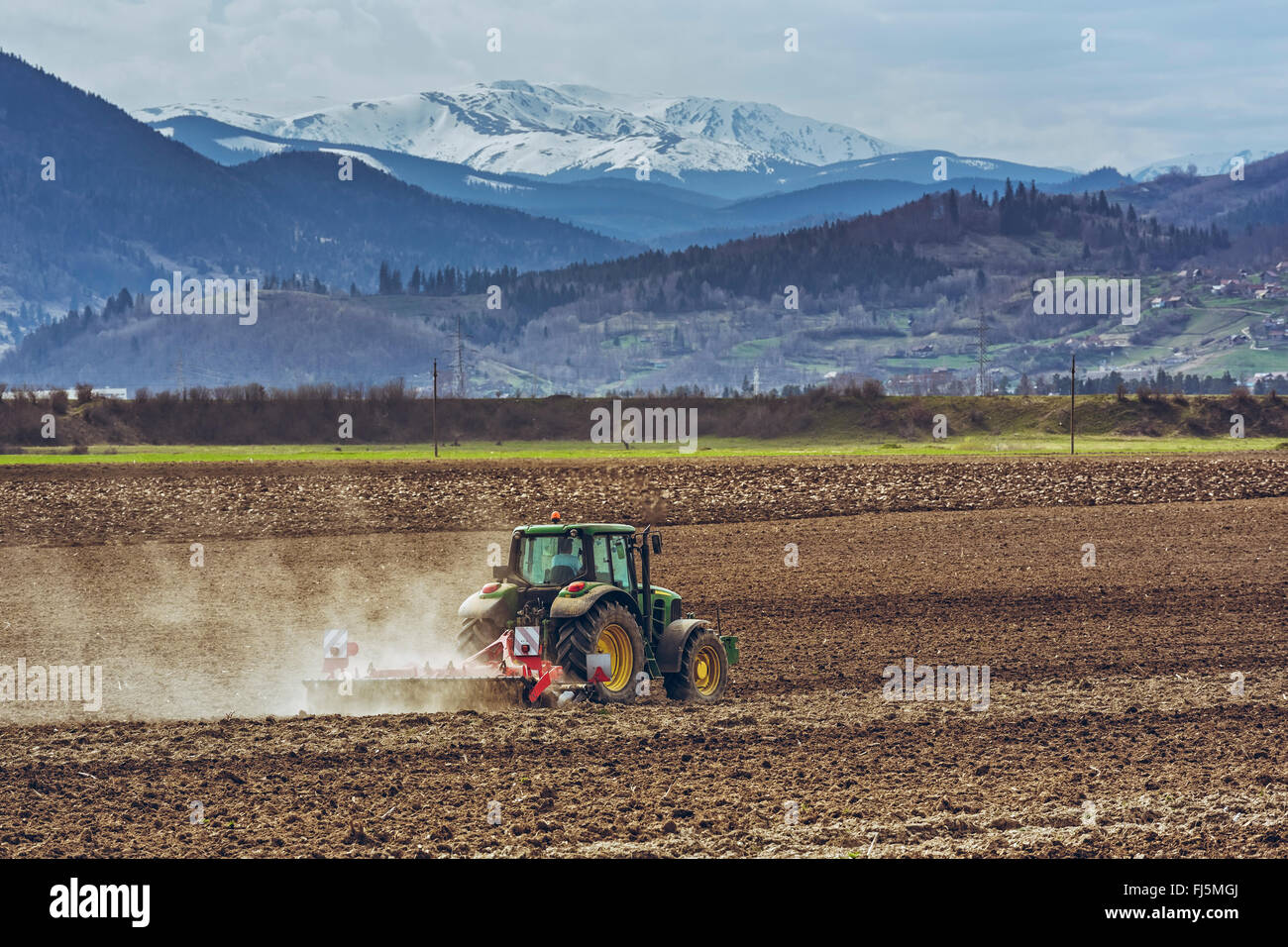 Modern tractor plowing fertile arable field in spring in Transylvania