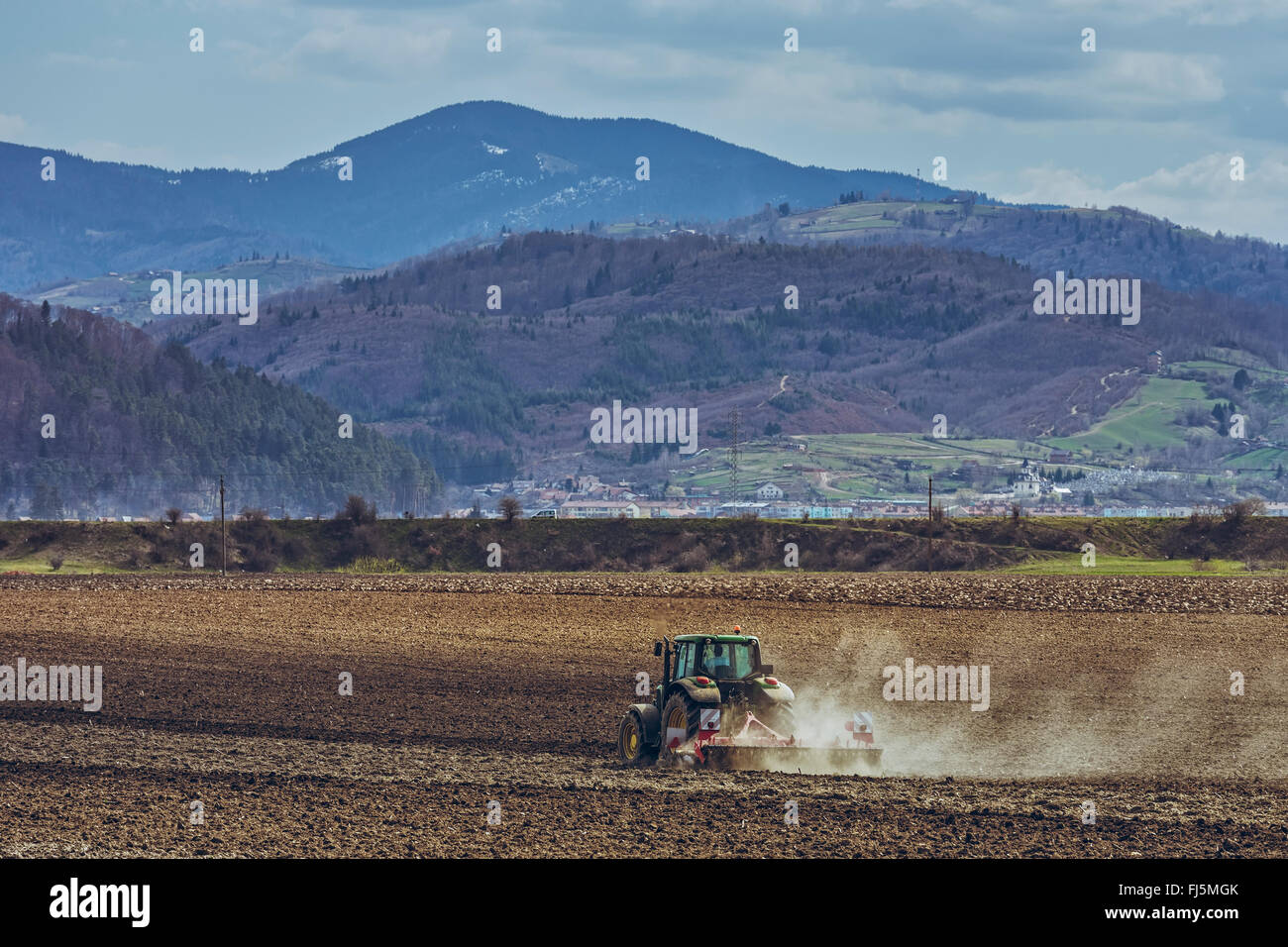 Modern tractor plowing fertile arable field in spring in Transylvania