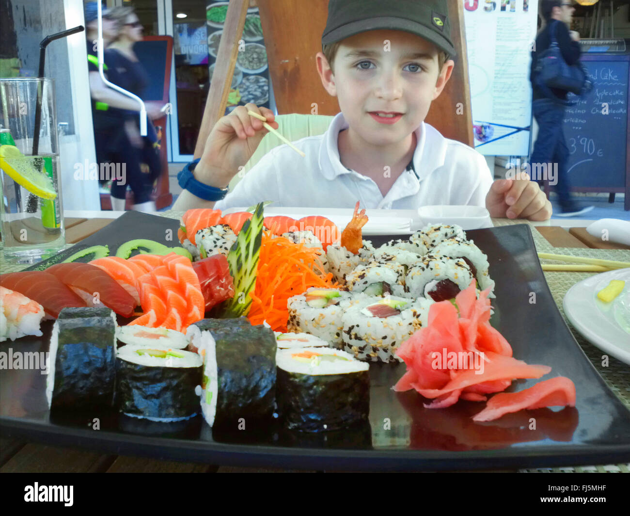 boy eating sushi in a sidewalk restaurant Stock Photo
