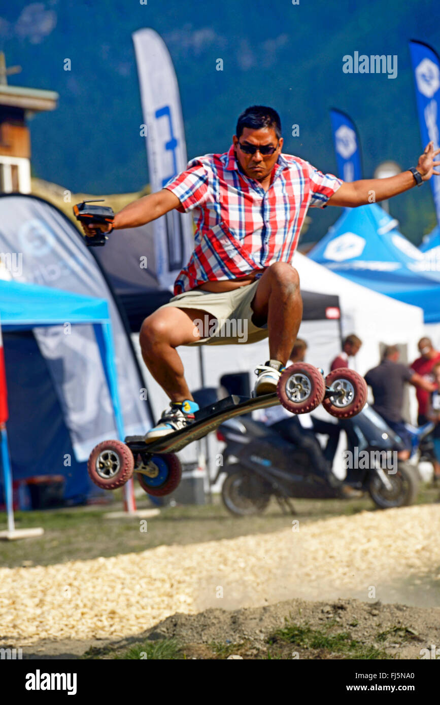 man jumping with an e-skateboard, France, Savoie Stock Photo