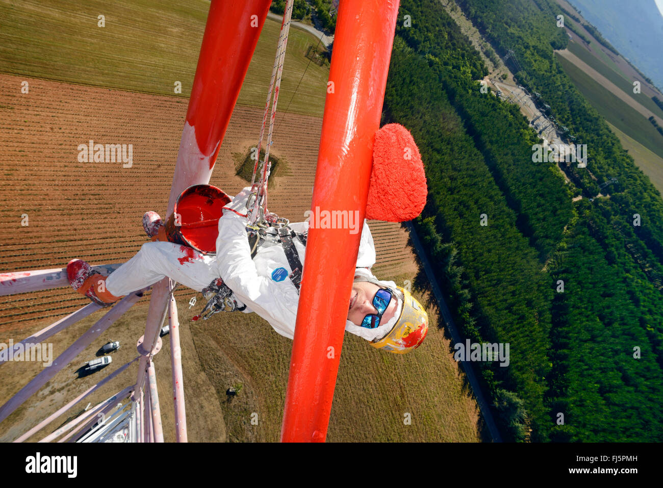 painter coating a pole in dizzy altidude, France Stock Photo