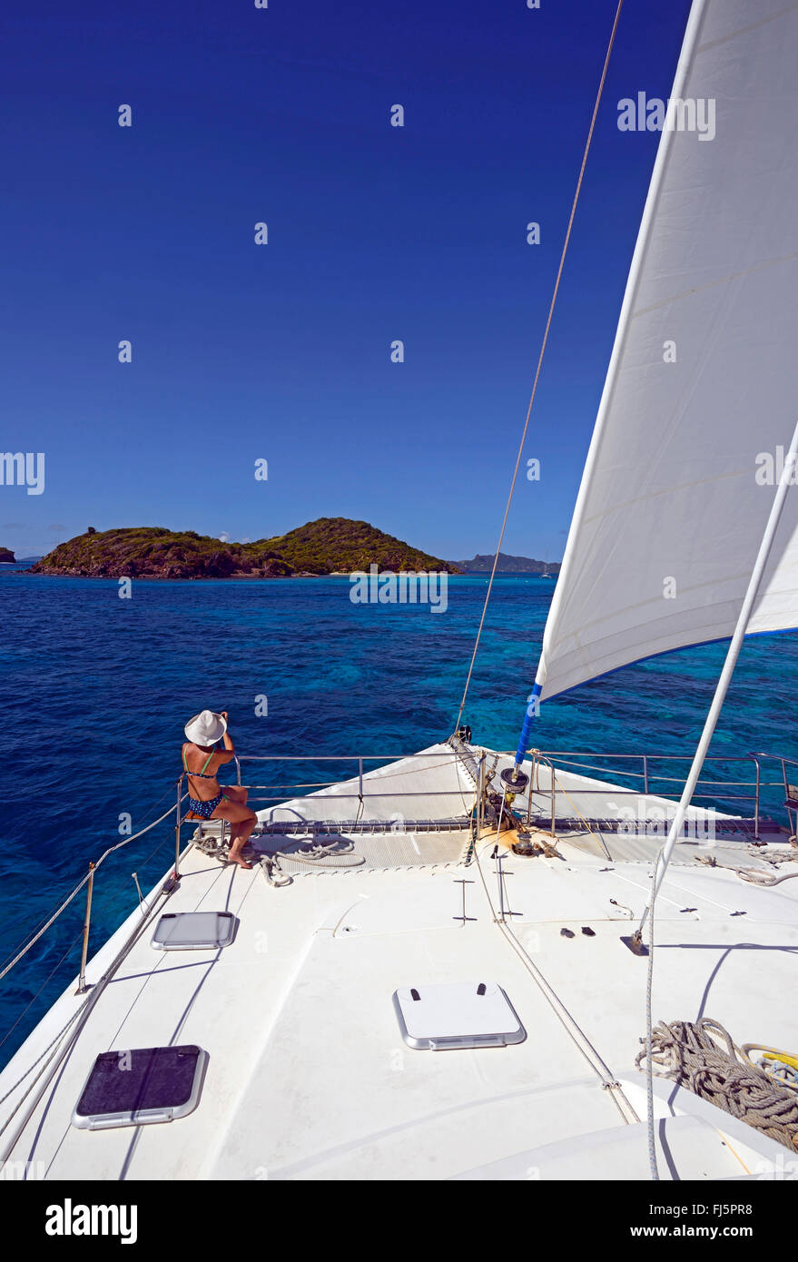 Woman taking pictures at the front part of catamaran sail boat in Tobago Cays, Saint Vincent and the Grenadines Stock Photo