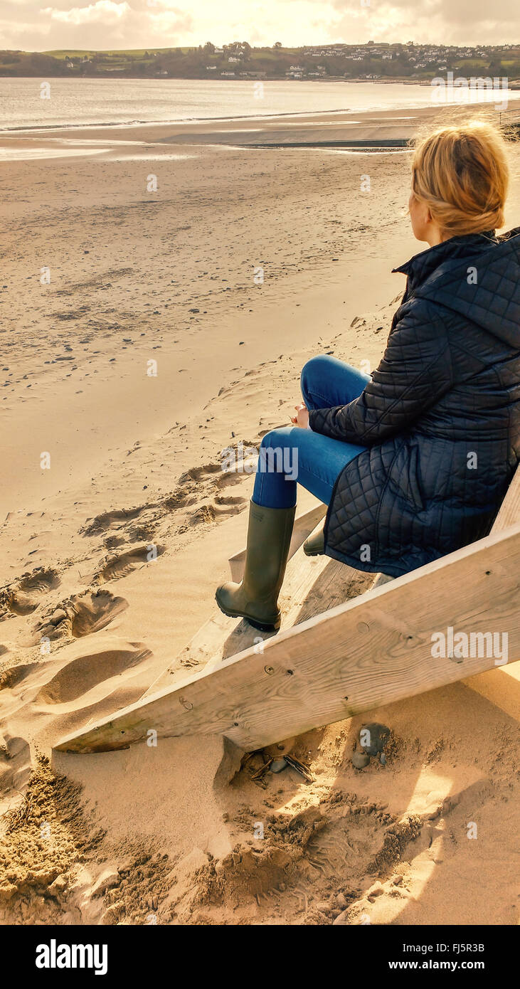 young blond female sitting on cabin stairs on beach Stock Photo