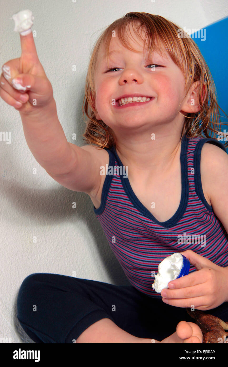 little boy putting on some lotion after bathing, Germany Stock Photo