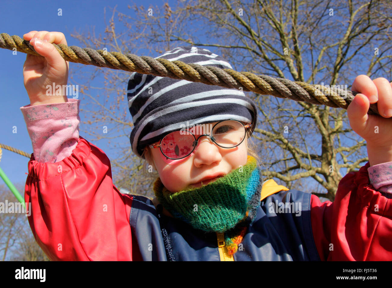 little girl with glasses and an eye patch holding on a rope, Germany Stock Photo