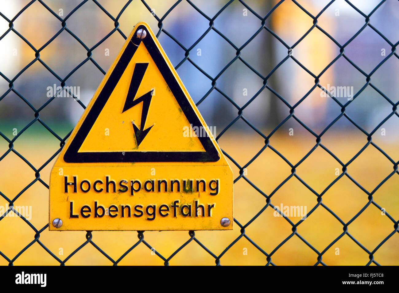 High voltage warning sign at a wire-mesh fence, Germany Stock Photo