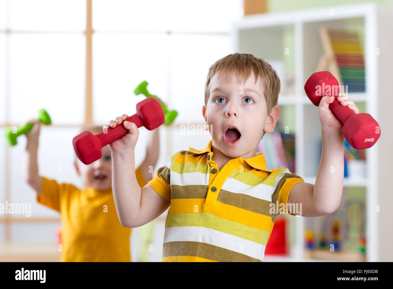 Funny kids boys exercising with dumbbells at home. Healthy life, sportive children. Stock Photo