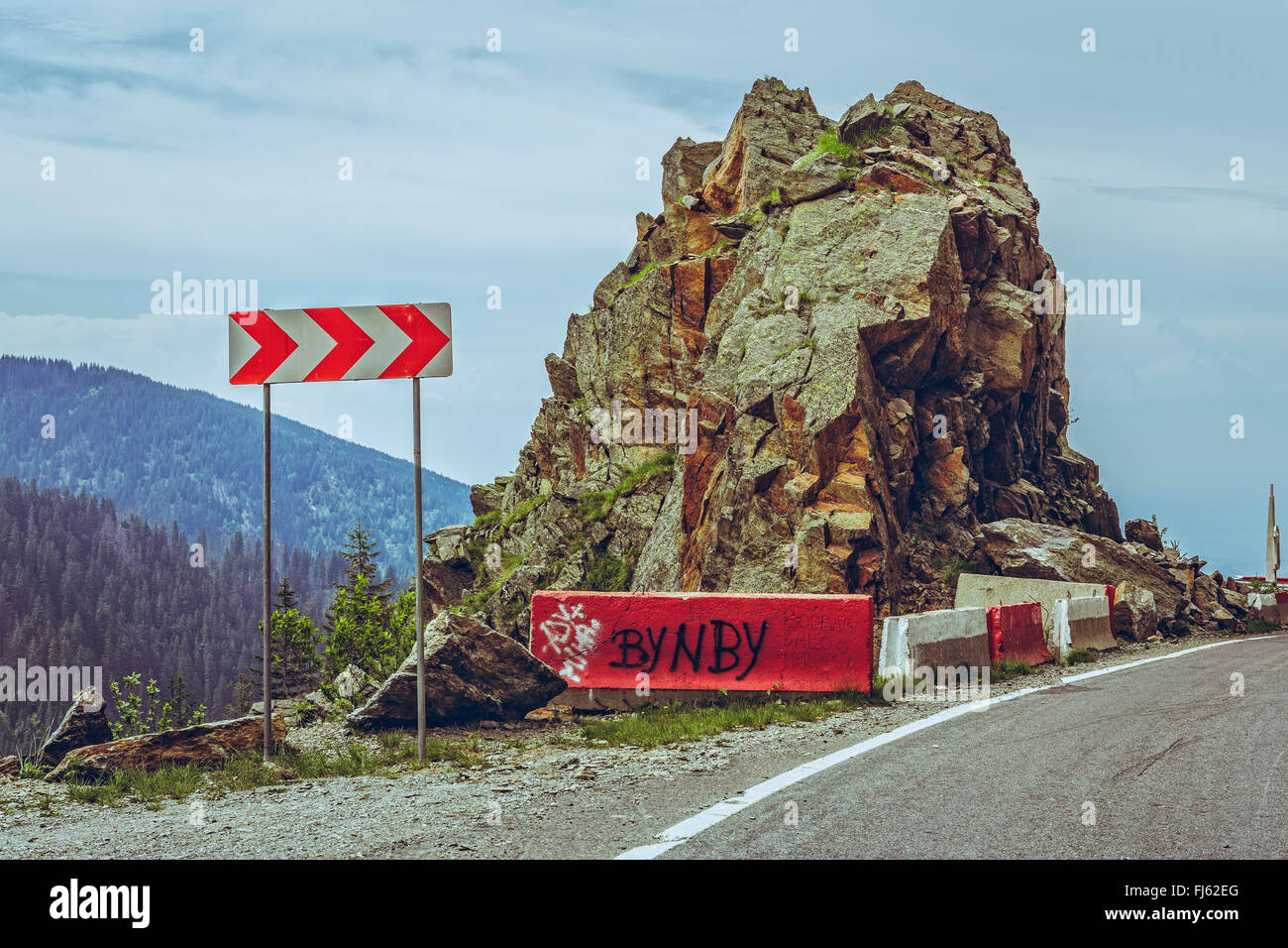 Roadside red and white triple chevron sign warning for dangerous road turn on sinuous Transfagarasan highway, Romania. Stock Photo