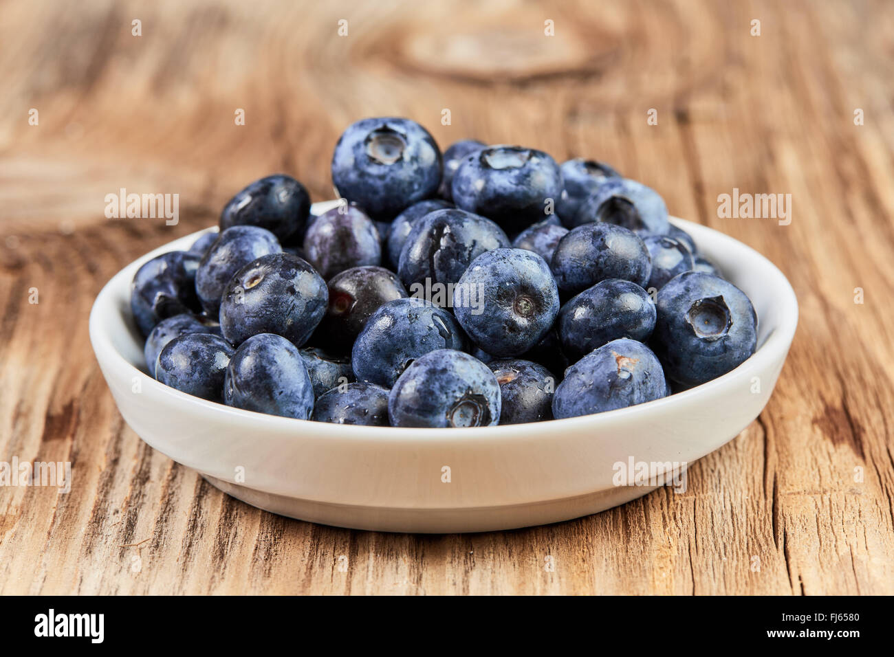 Huckleberries super food in a white china dish on a brown wooden table Stock Photo