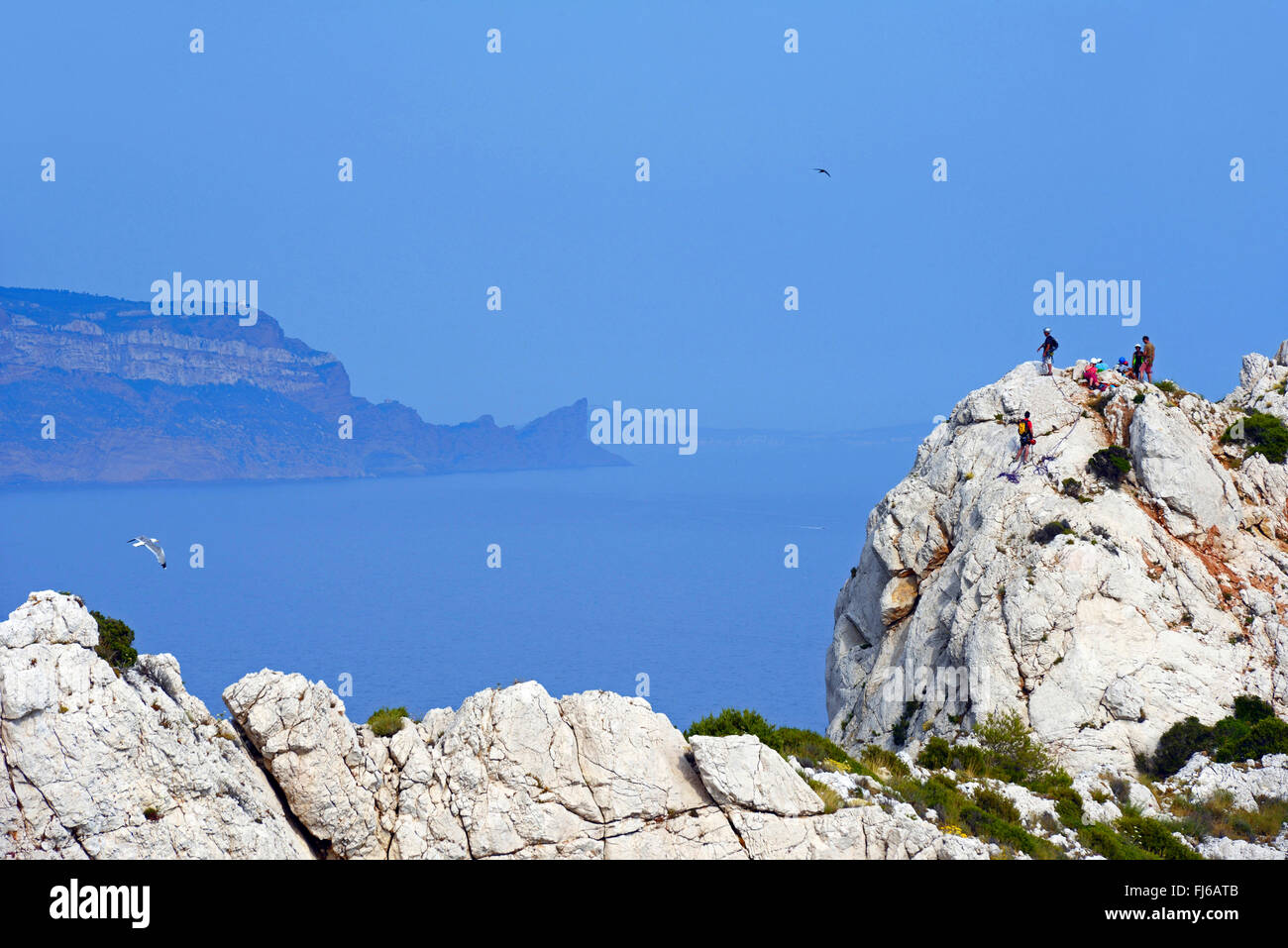 climbers on the coastal rock of Calanque de Sormiou, Cap de l'Aigle in the background, France, Calanques National Park Stock Photo