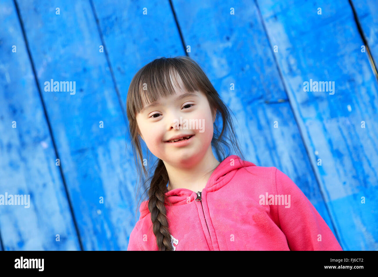 Young girl smiling on background of the blue wall Stock Photo