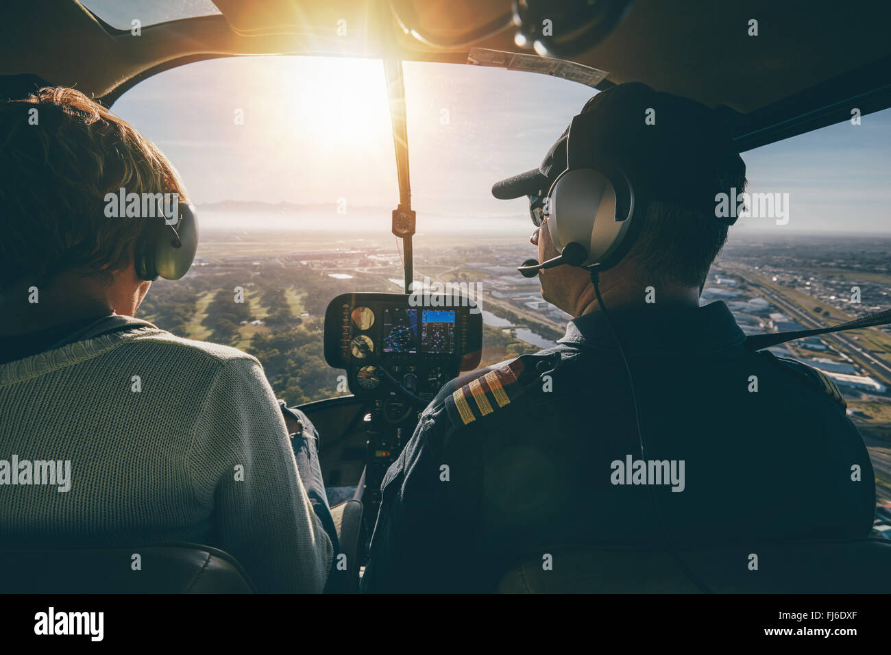Inside view of a helicopter in flight, with man and woman pilots flying a helicopter on a sunny day. Stock Photo