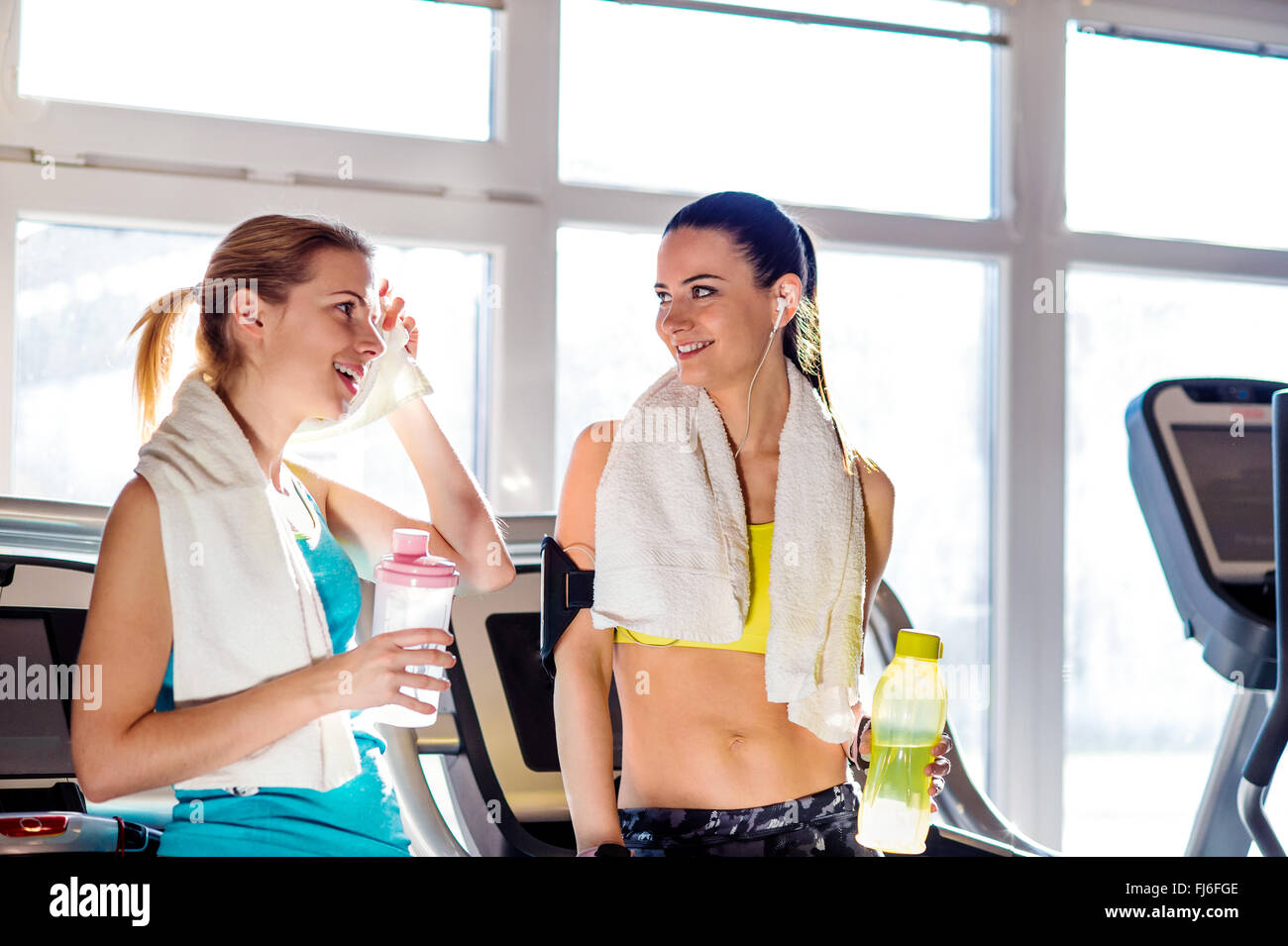 Two women in gym with water bottles and towels Stock Photo - Alamy