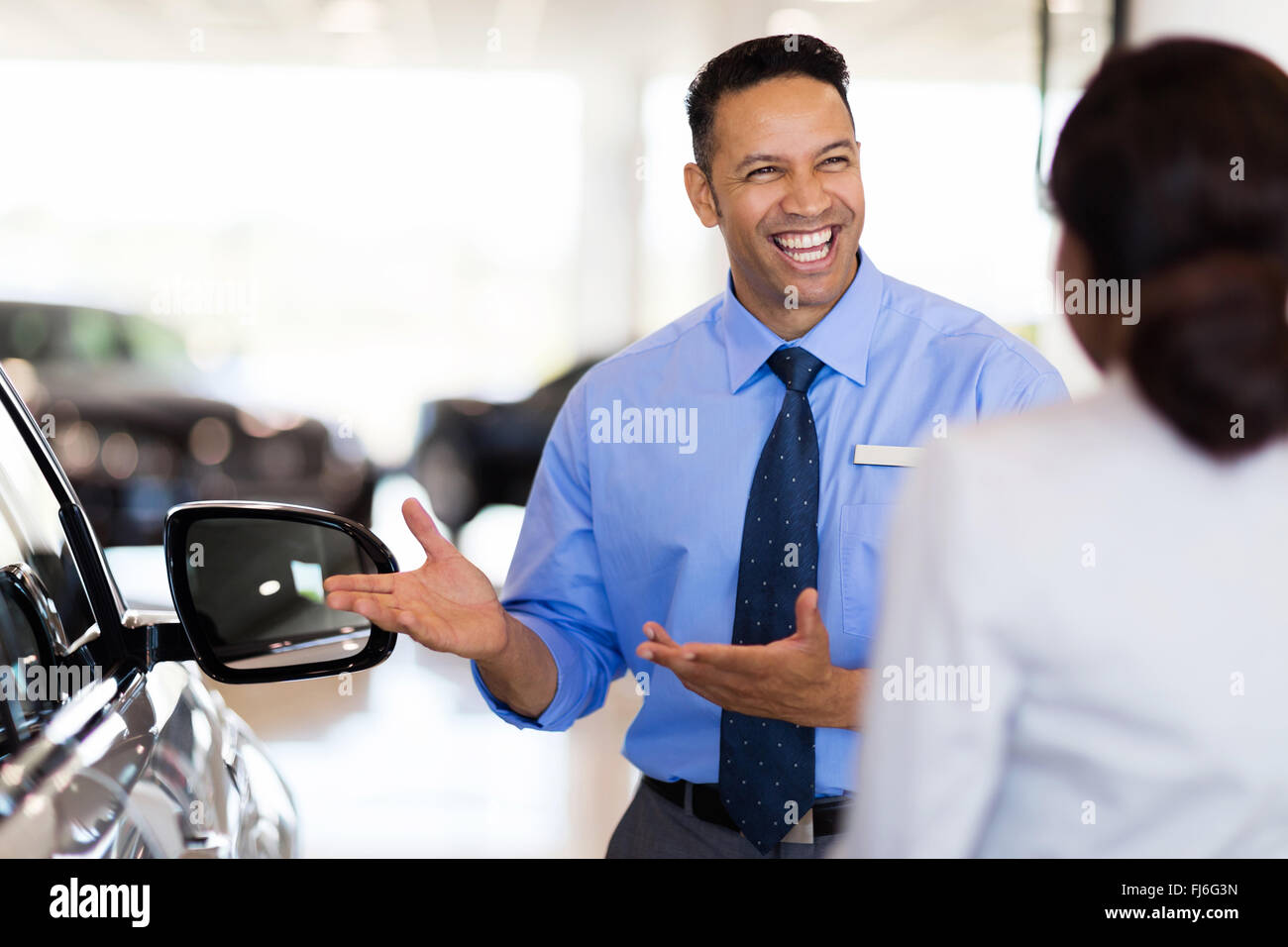 friendly vehicle dealer showing young woman new car Stock Photo