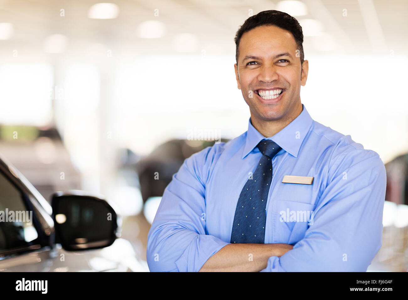 cheerful car salesman standing in showroom Stock Photo