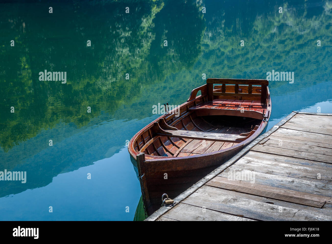 Wooden boat, sky and forest reflected in the mirror lake water Stock Photo