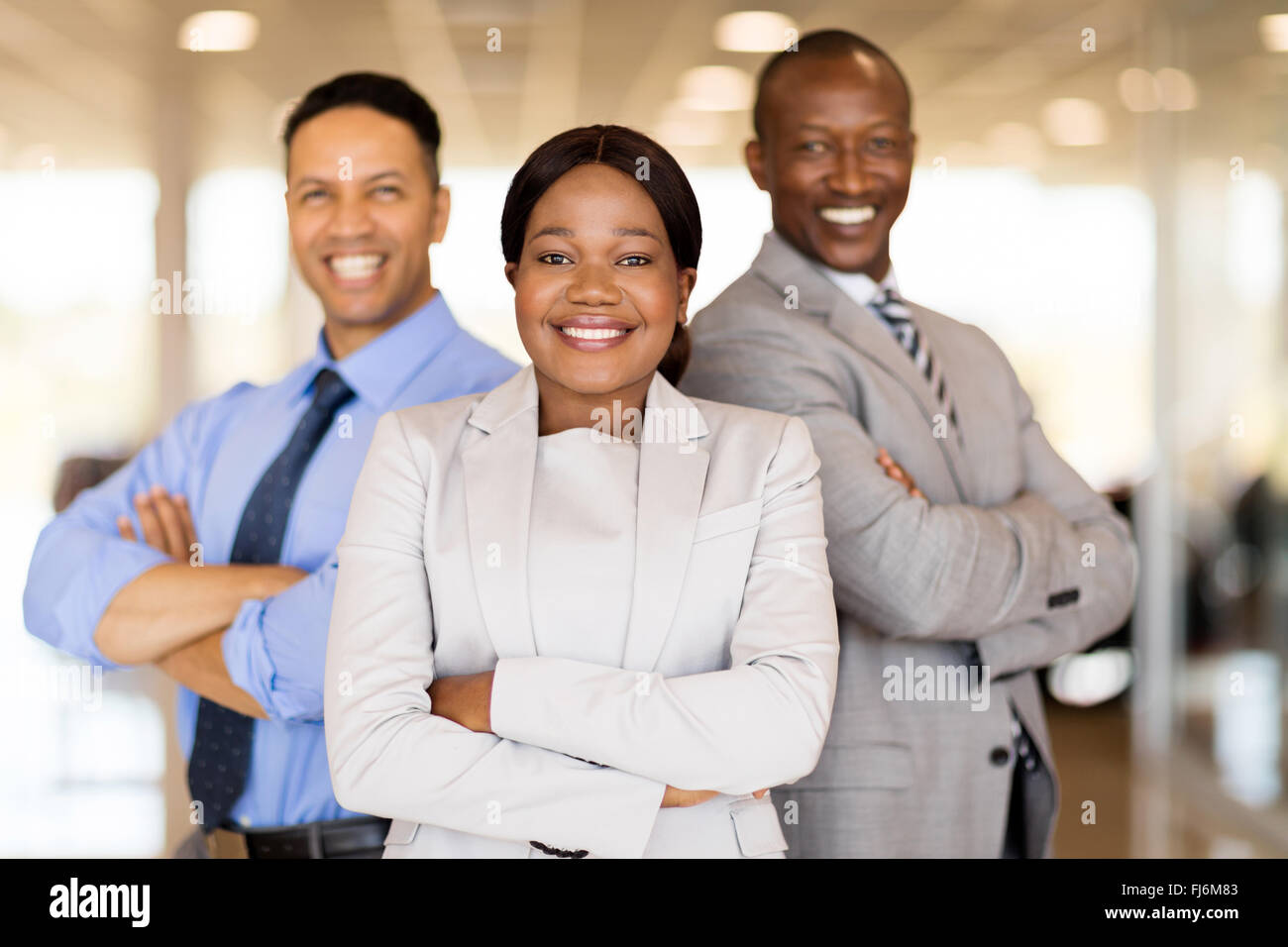 multiracial vehicle sales team with arms crossed inside car showroom Stock Photo