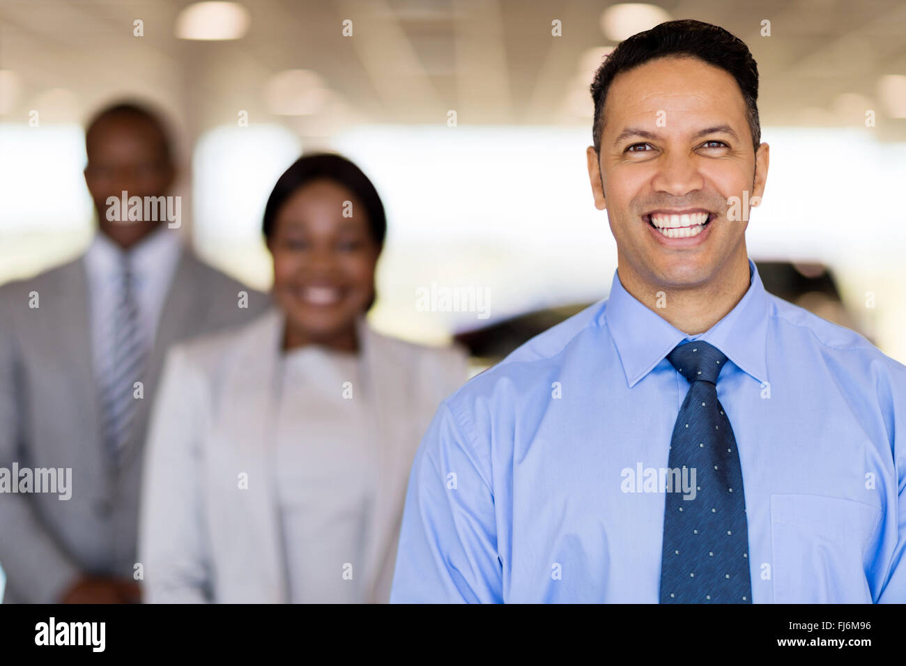 cheerful car dealership principal with staff on background Stock Photo