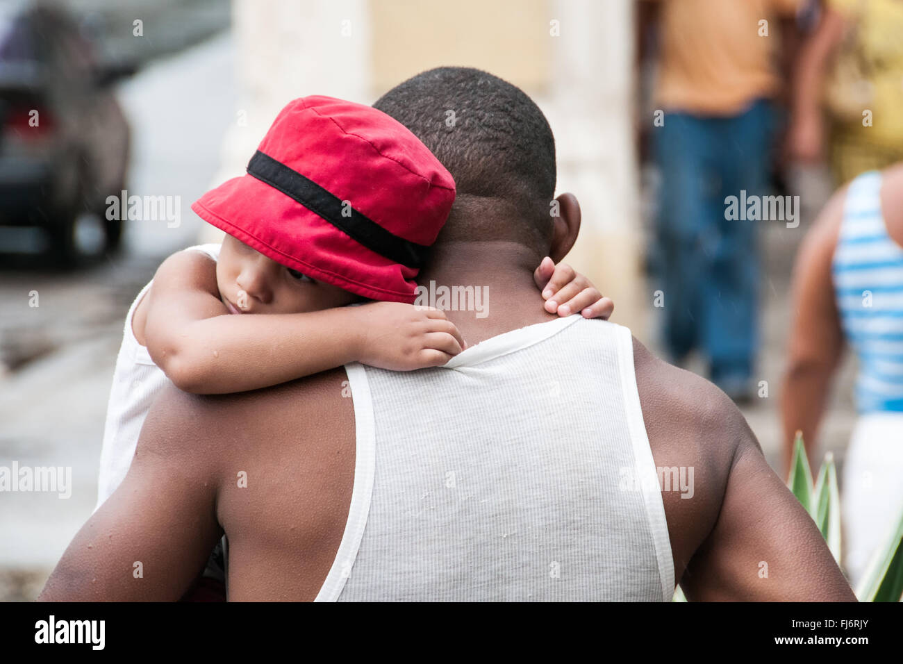 father who protects the child from the rain - Cuba Stock Photo