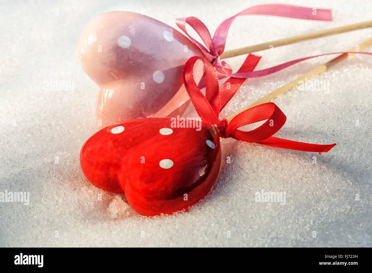 Valentines Day, two red hearts on ice wet snow, selective focus Stock Photo