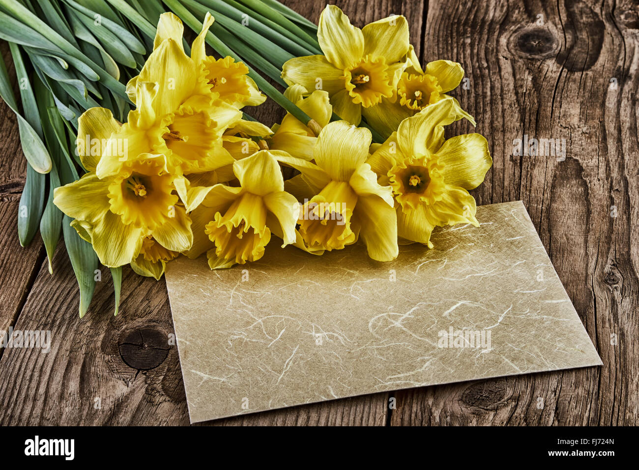 Easter Vintage Style yellow flowers paper sheet on old wooden board Stock Photo