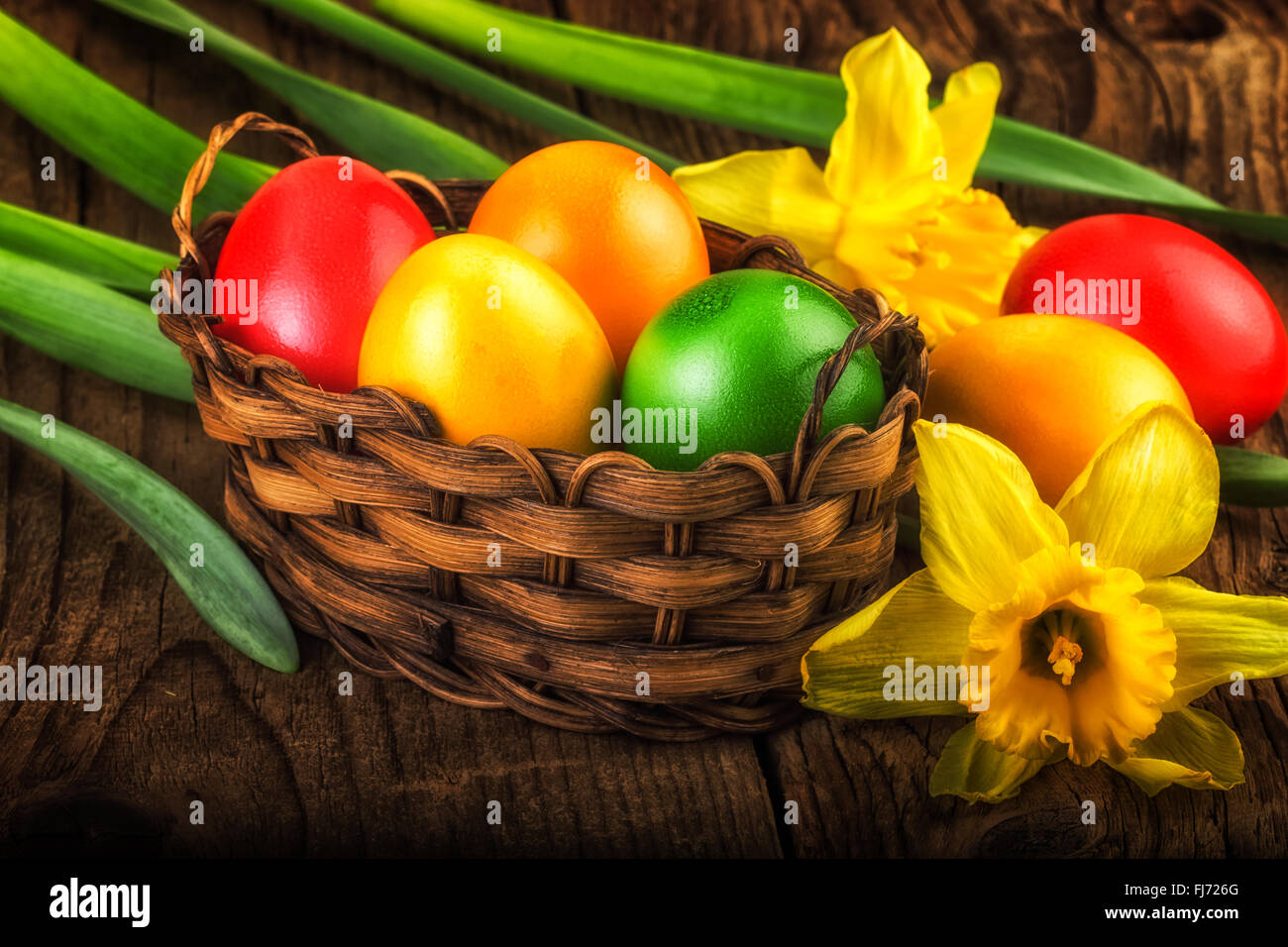 Colorful Easter decoration on dark wood with sunlight effect Stock Photo