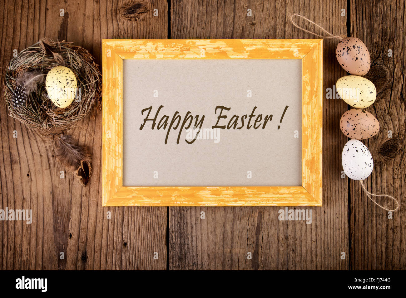 Easter decoration on old wood vintage style. Yellow wooden frame with text Happy Easter. Stock Photo