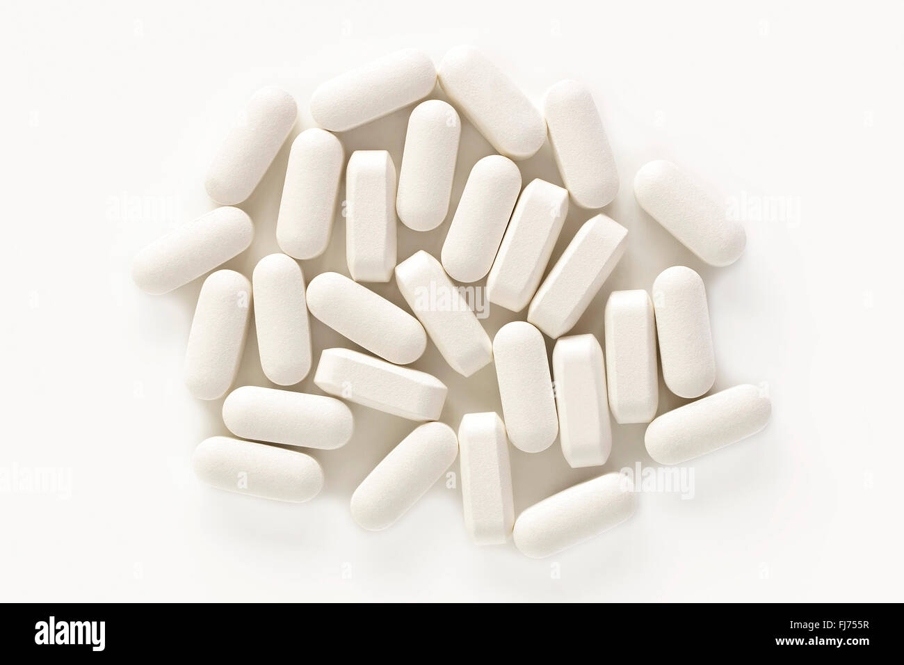 A pile of calcium vitamin supplement tablets isolated on a white background from above. Stock Photo
