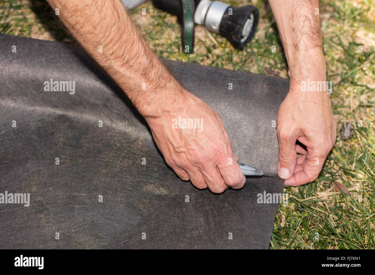 A man preparing a clay pot for a garden by creating a hole and base in ground, then filling and planting with garden soil Stock Photo