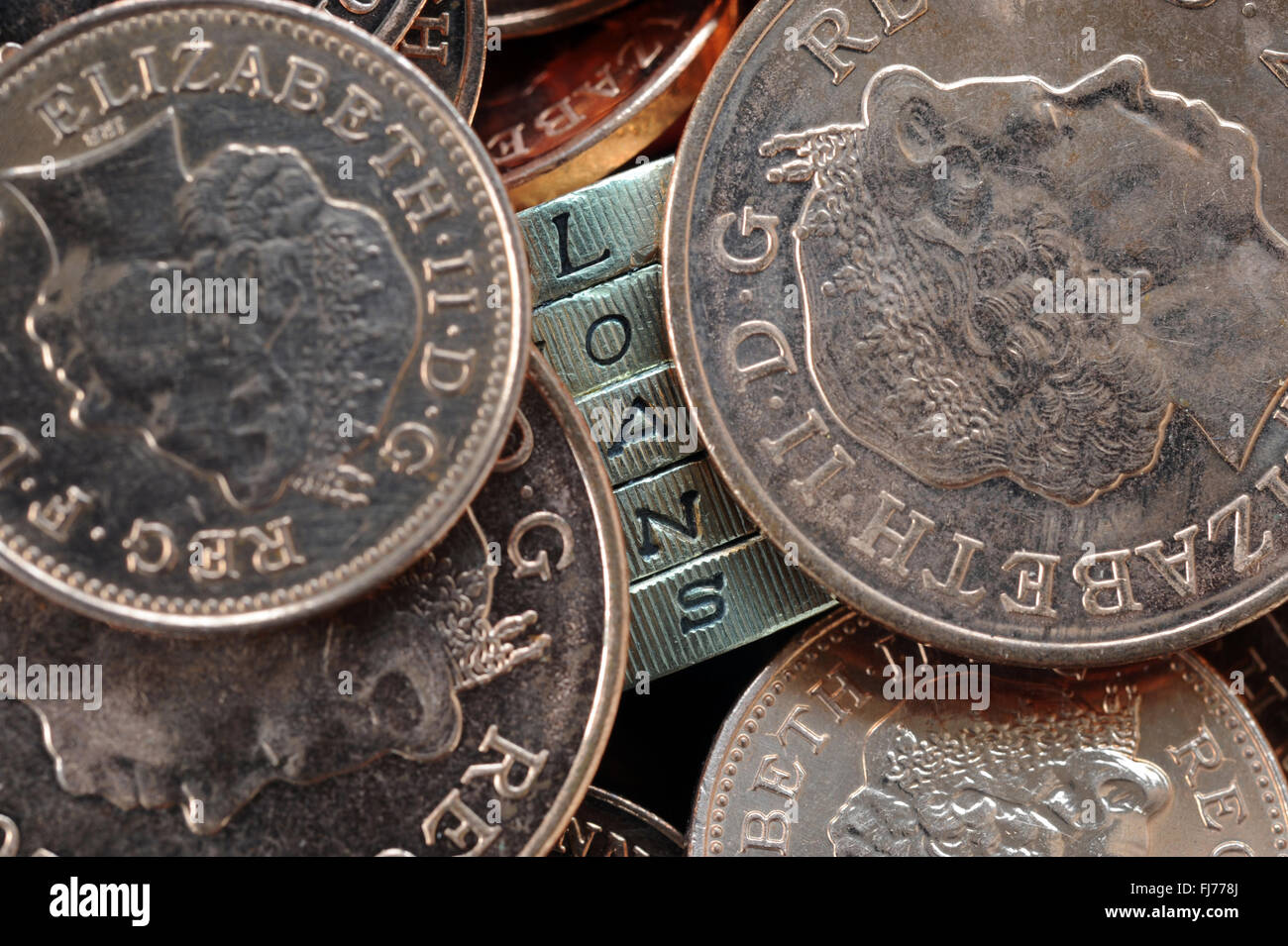 ONE POUND COIN EDGE LETTERS SPELLING WORD 'LOANS' WITH COINS RE PAY DAY LOANS BORROWING INTEREST RATE MORTGAGES HOUSE BUYING UK Stock Photo