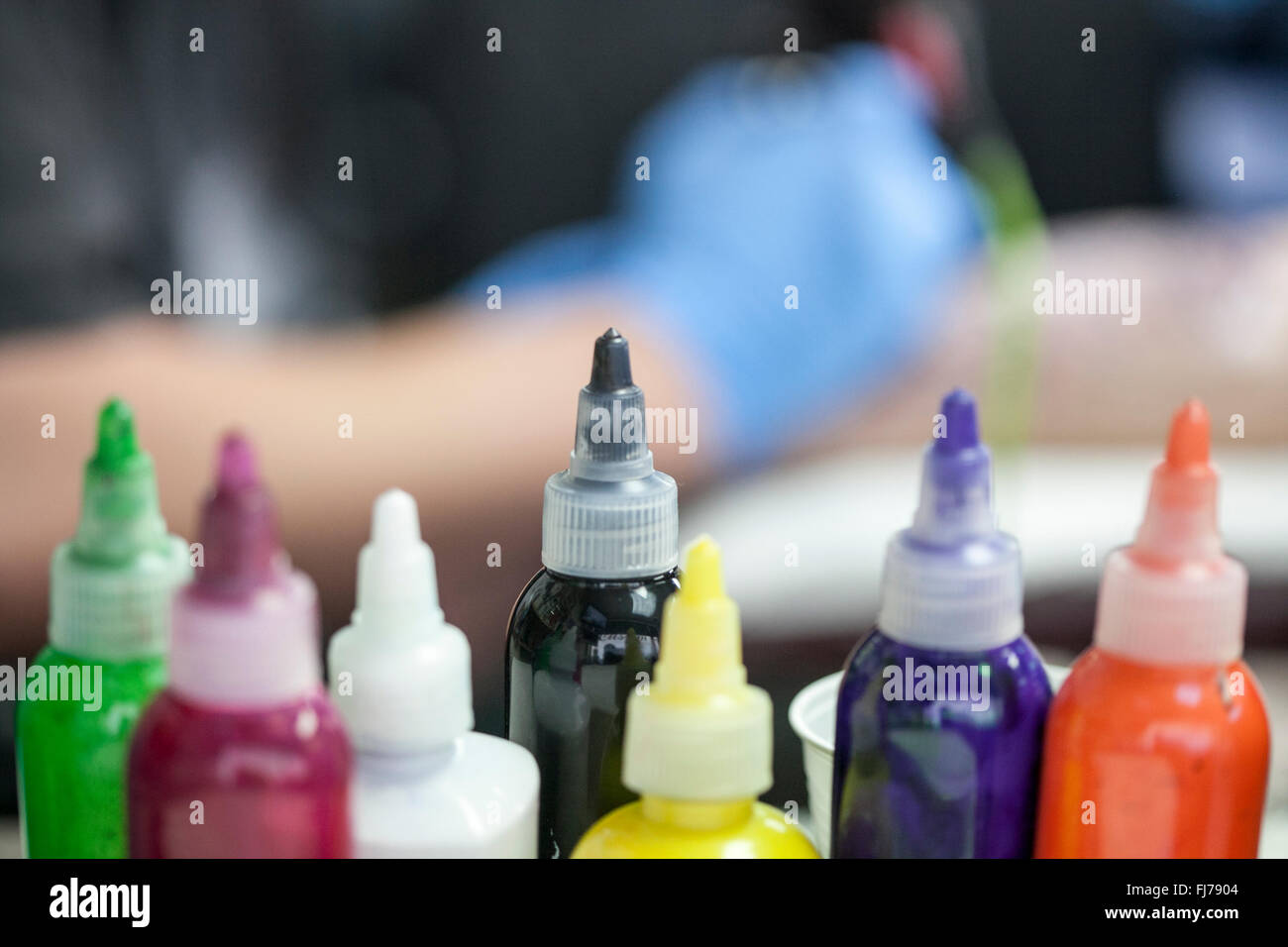 Ink bottles and tattoo artist inking a client with a biomechanical