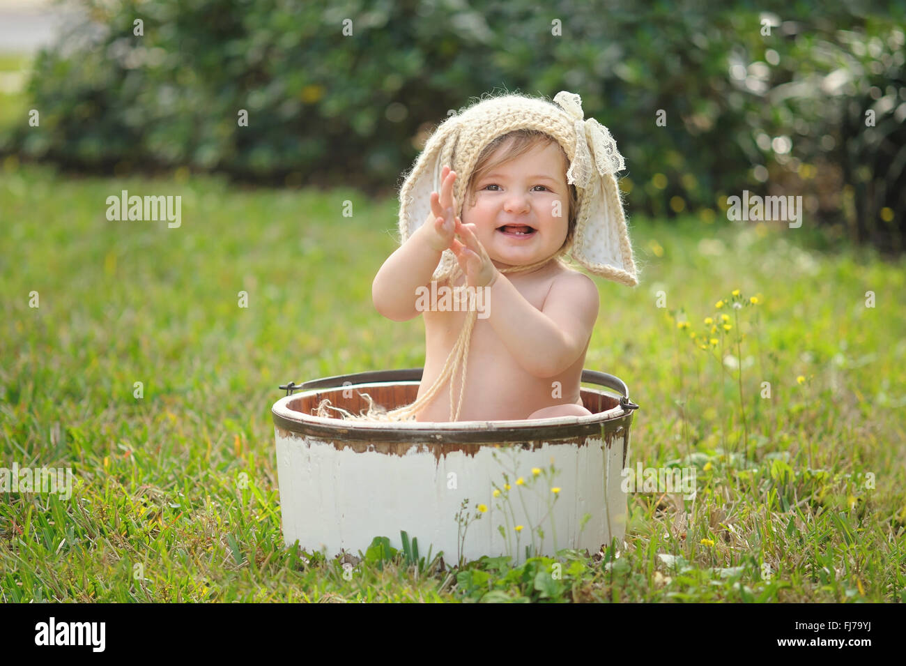 A smiling baby girl wearing a crocheted, bunny bonnet. Stock Photo