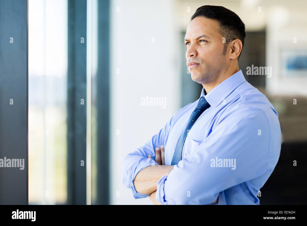 thoughtful mid age businessman with arms crossed Stock Photo