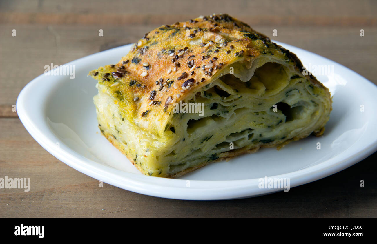 Saucer with spinach and cheese pie on a wooden table Stock Photo