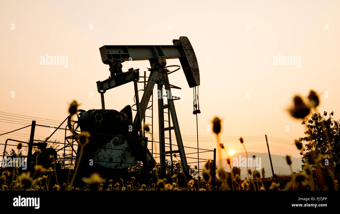 pumpjack at an oil drilling site and sunset Stock Photo