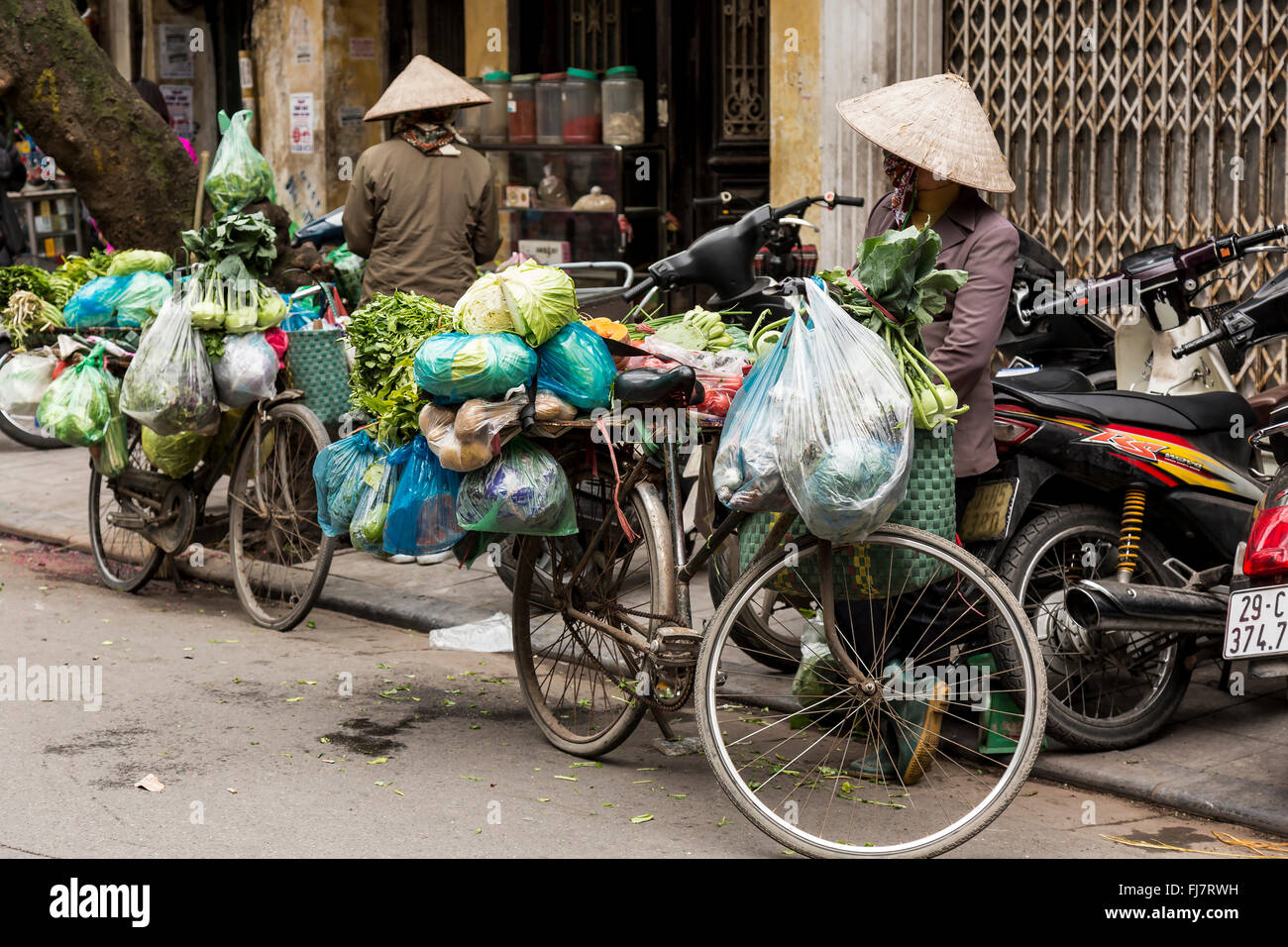 Hanoi, VIetnam - February 2016. Street vendors in Hanoi walking around with their bicycles. Stock Photo