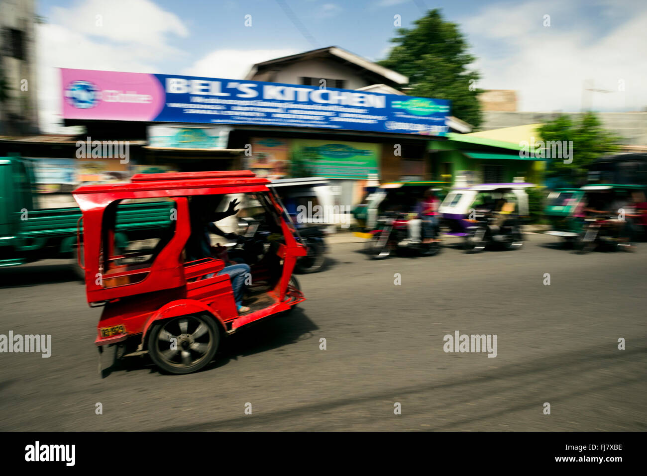 Kalibo, Philippines - February 10, 2016. Red tricycle and the driver waving his hand to the camera. Stock Photo