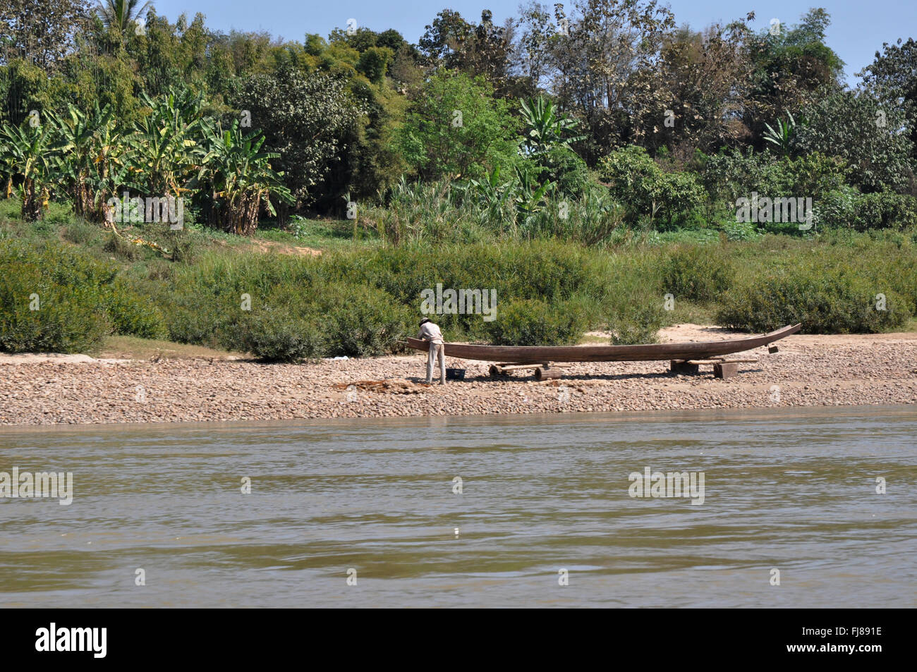 Laotian working on a traditional boat, Mekong river, Laos Stock Photo