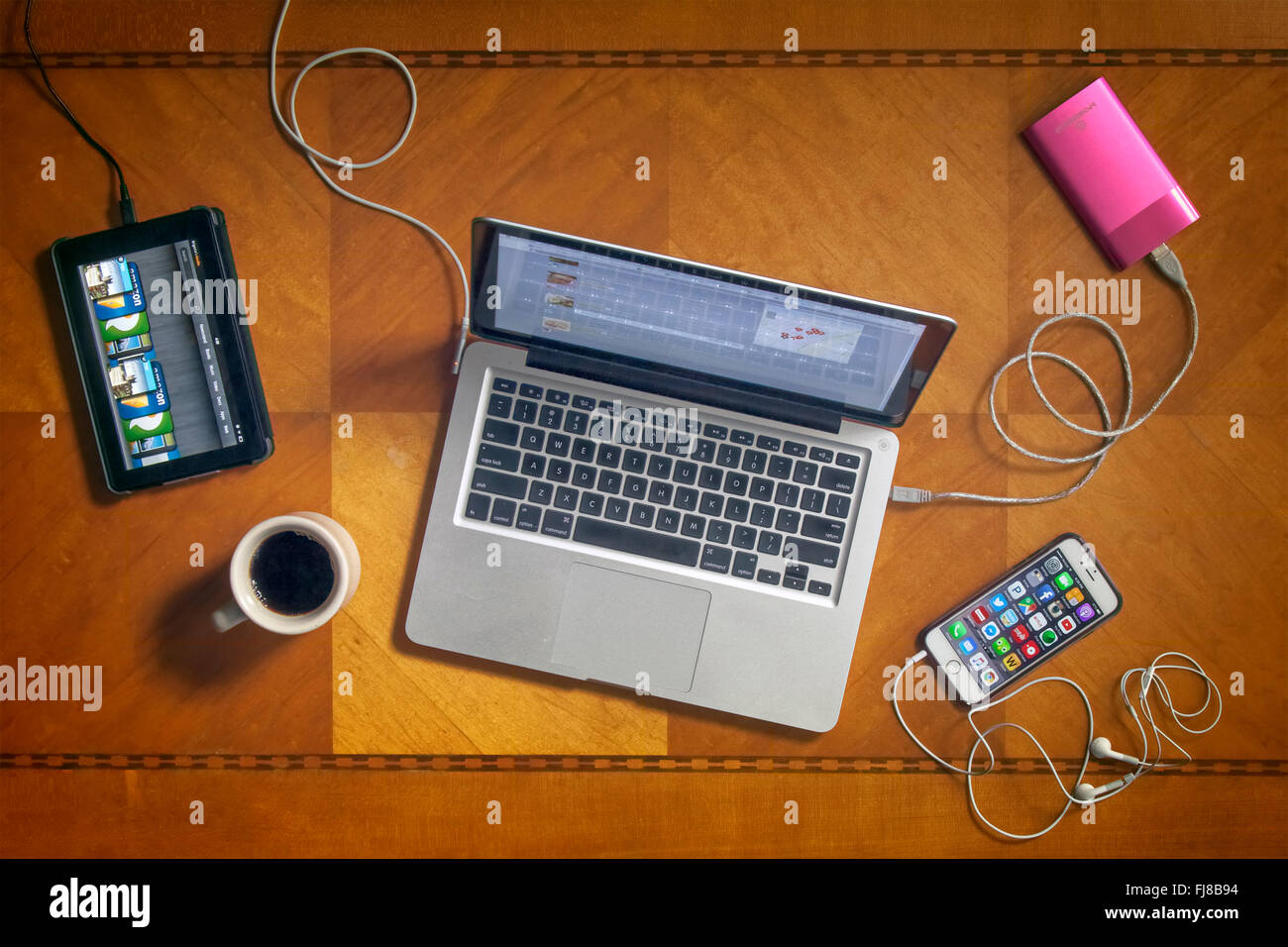 Looking down on an art deco table top with a laptop computer,kindle fire,iphone,cup of coffee and charging device Stock Photo