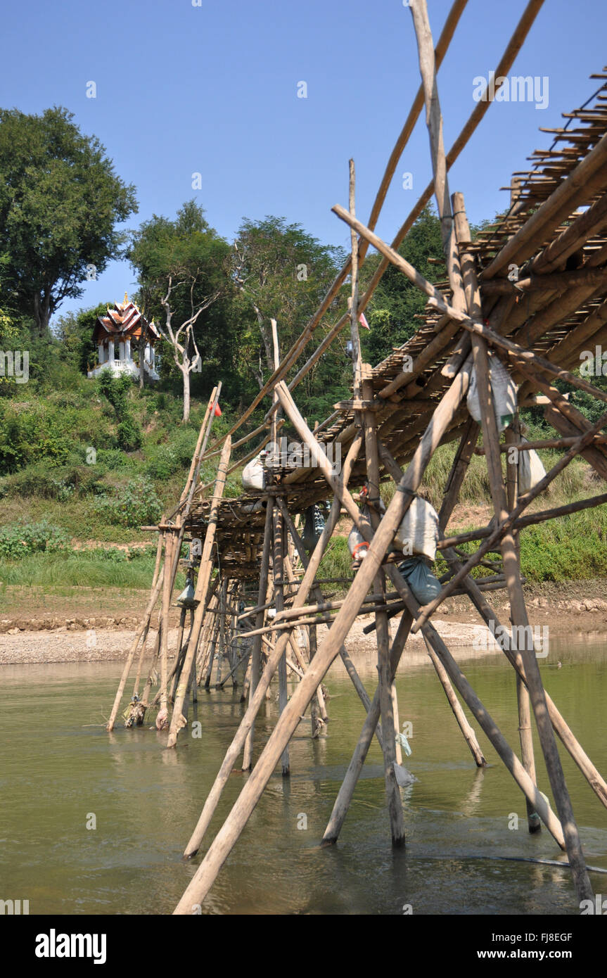 Bamboo bridge across the Nam Kham River, temple at the top of the hill ...