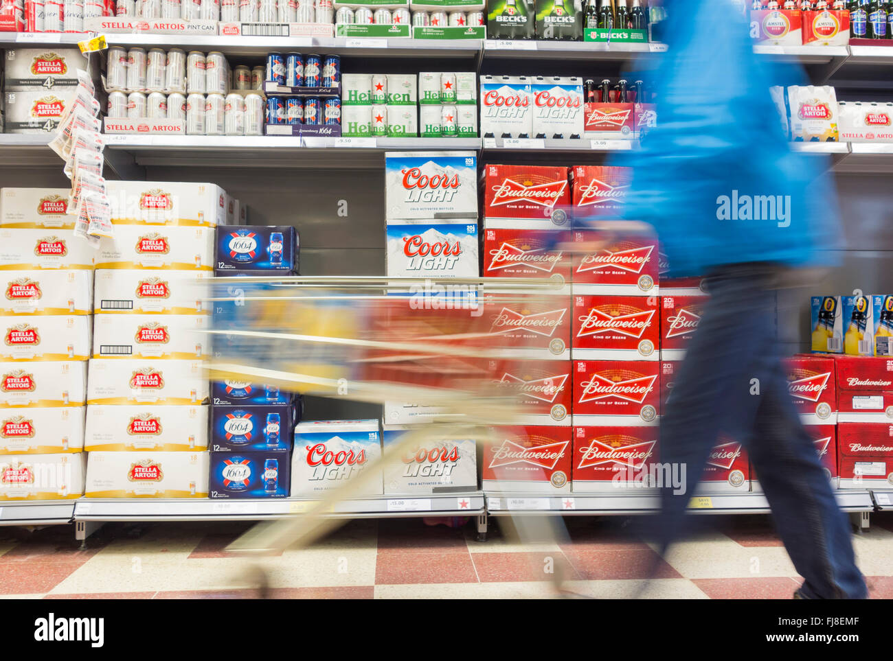 Man with cases of beer in shopping trolley in supermarket. UK Stock Photo