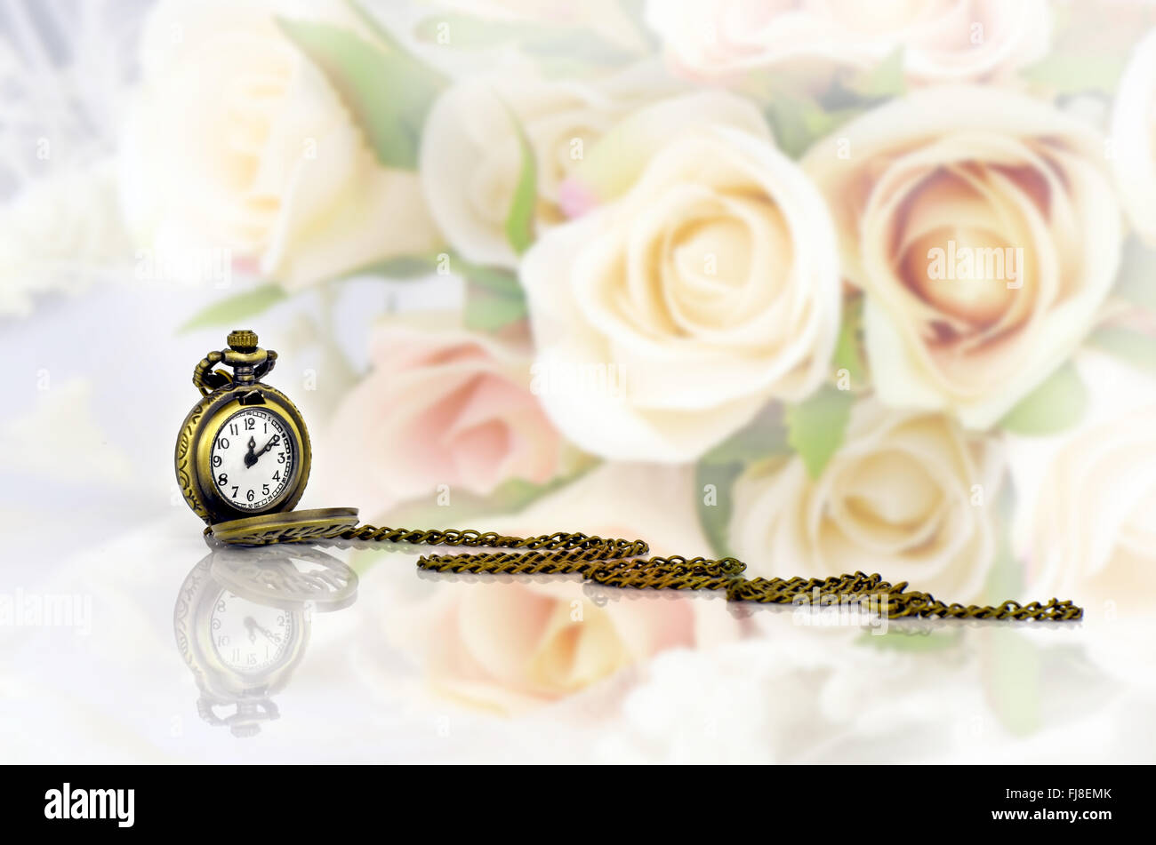 Vintage pocket watch with rose bouquet on pastel tone background. Stock Photo
