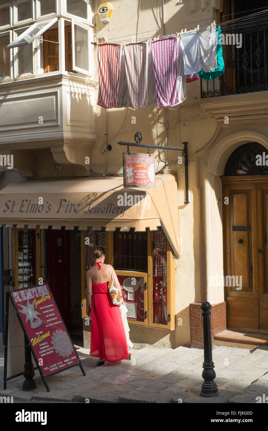 Woman in a red dress outside a shop in Republic Street,Valletta,Malta Stock Photo