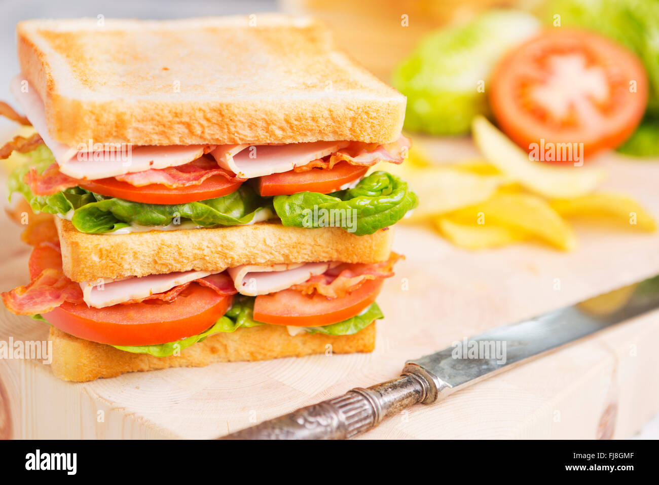 A club sandwich on a rustic table in bright light. Stock Photo