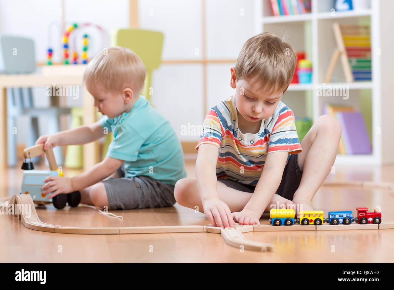 Children playing with educational toys and building rail road Stock Photo
