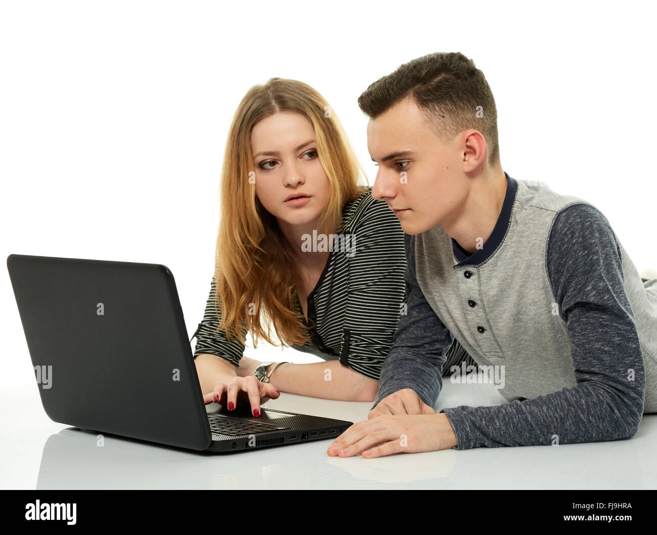 Teenage boy and girl students, doing homework together on a notebook ...