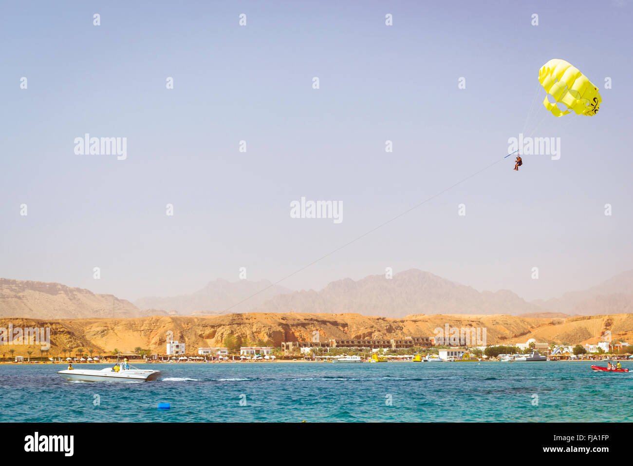 SHARM EL SHEIKH, EGYPT - FEBRUARY 23, 2014: Parachuting over a sea, towing by a boat: happy couple is flying on a parachute Stock Photo