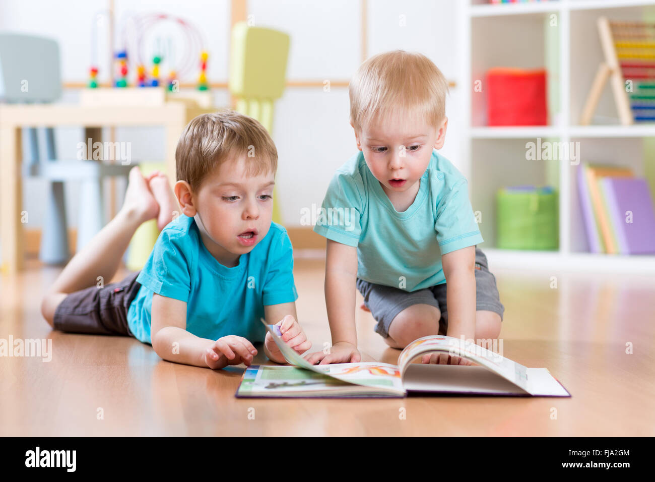 happy kids boys brothers reading encyclopedia together at home Stock Photo